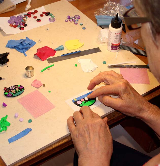 hands making jewellery surrounded by small items to be used