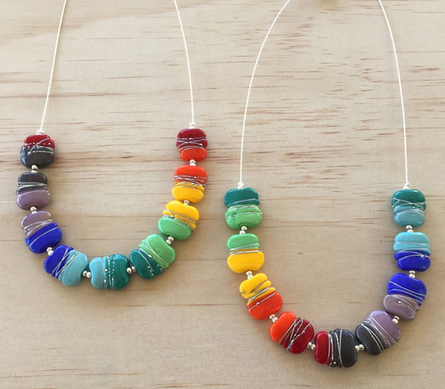 2 rainbow glass necklaces on wooden background