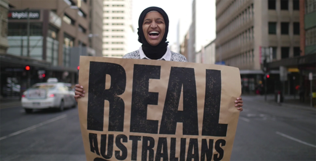Happy women holding 'Real Australians Say Welcome' in a city street