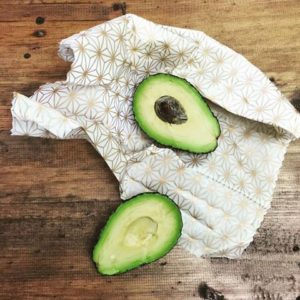 fresh avocado cut in half resting on star patterned food wrap on a wooden surface