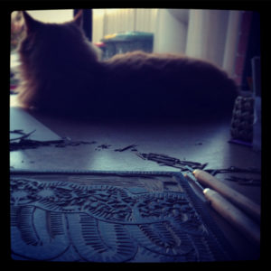 Orange Cat beside a carved lino print in progress