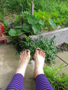 bare feet beside a garden bed with nasturtiums growing in it