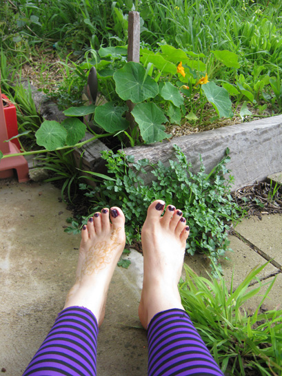 bare feet beside a garden bed with nasturtiums growing in it