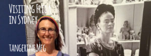 Header image for "Visiting Frida in Sydney" blog post featuring Tangerine Meg posing in front of a big photographic mural of Frida Kahlo in her studio.