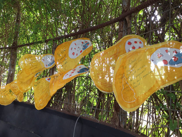 Yellow flags flying leftwards under a green leafy canopy