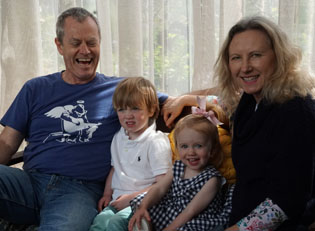 Two adults and two children sitting together in front of a curtained window.