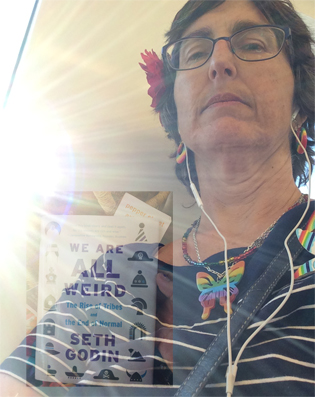 me on the train with the sunshine behind me, overlaid with seth godin book entitled "we are all weird"