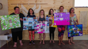 6 beautiful souls holding up their vision boards for 2018 in a wood-lined yoga studio