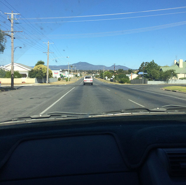 view out a windscreen at a road and a blue sky