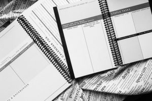 Black and white photo of a large and a small Freelancer Planner opened up so you can see the page layouts.